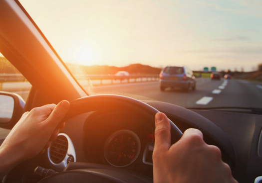 Hands on a steering wheel while driving.